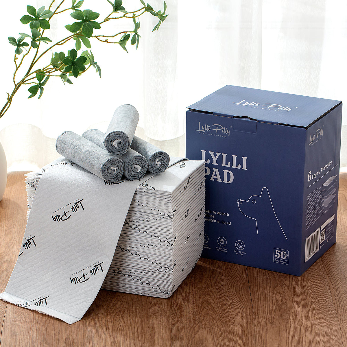Lylli Pad box and loose pads arranged on a timber floor beside a window, showing the quilted pad surface