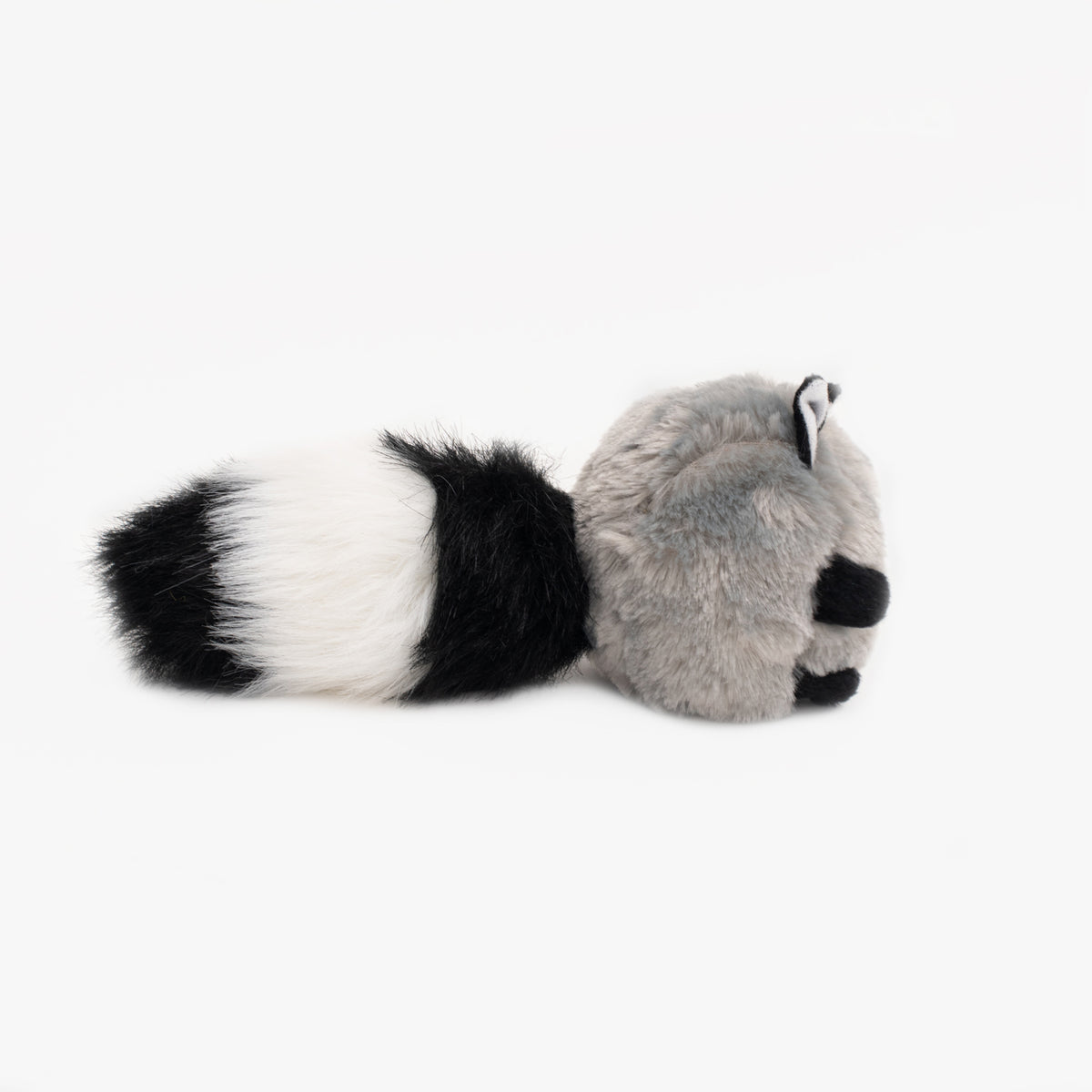Dog carrying the Zippy Paws Bushy Throw Raccoon by the tail
