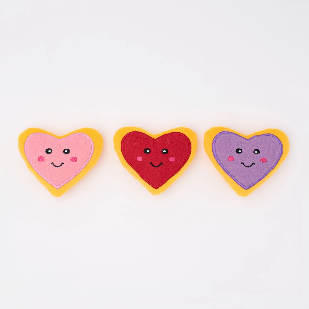 Three Zippy Paws Miniz heart-shaped plush cookie dog toys in pink, red and purple