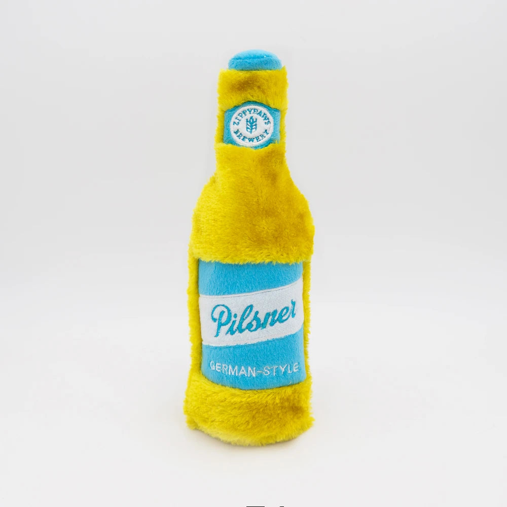 Zippy Paws Happy Hour Crusherz plush dog toy shaped as a pilsner beer bottle, on white