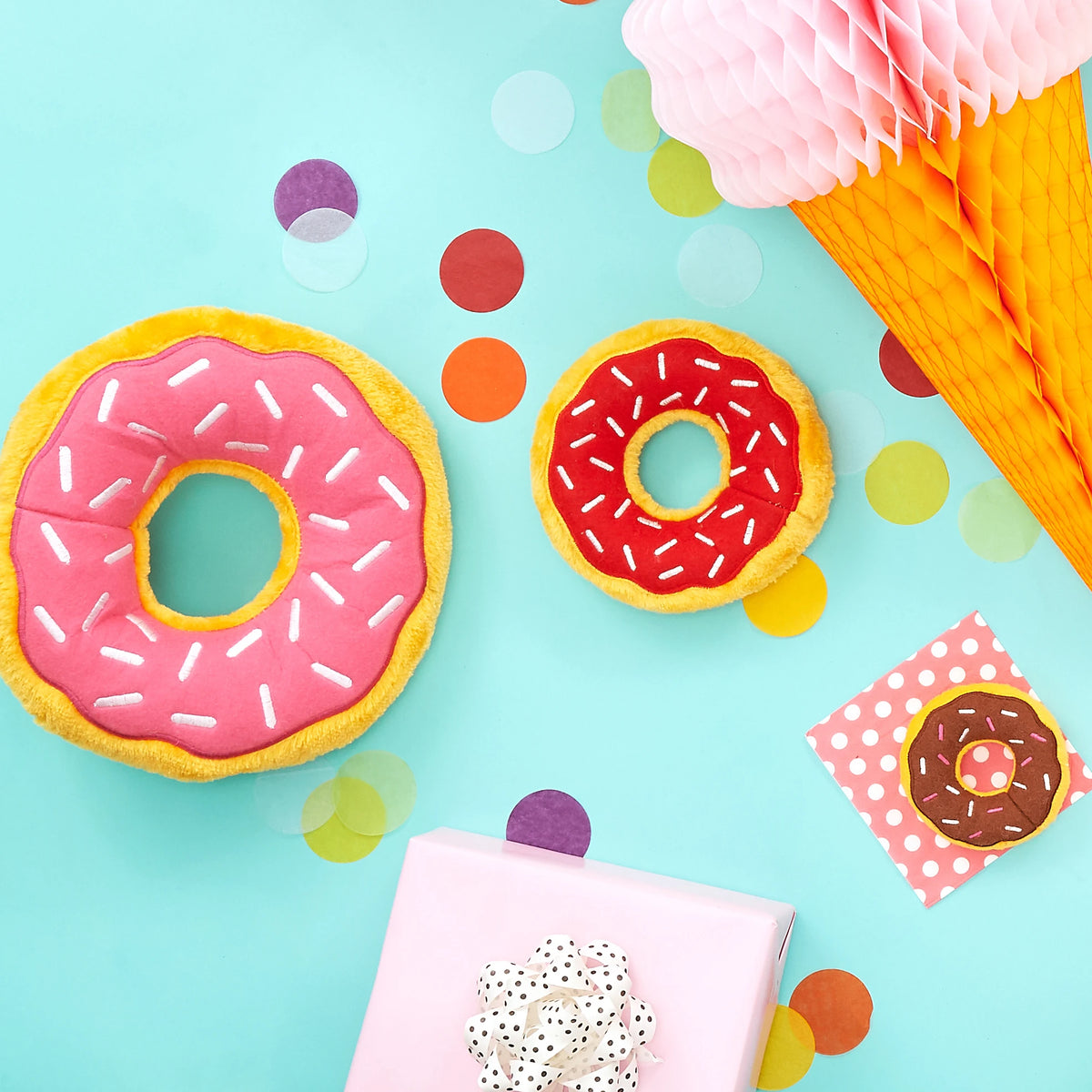 Flat lay of two Zippy Paws Donutz Jumbo plush dog toys on a teal party backdrop