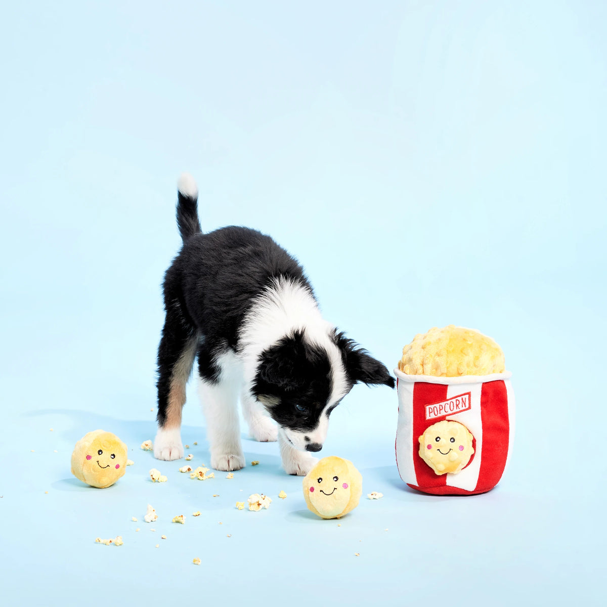 Black and white cat playing with a Zippy Paws Burrow popcorn bucket plush toy