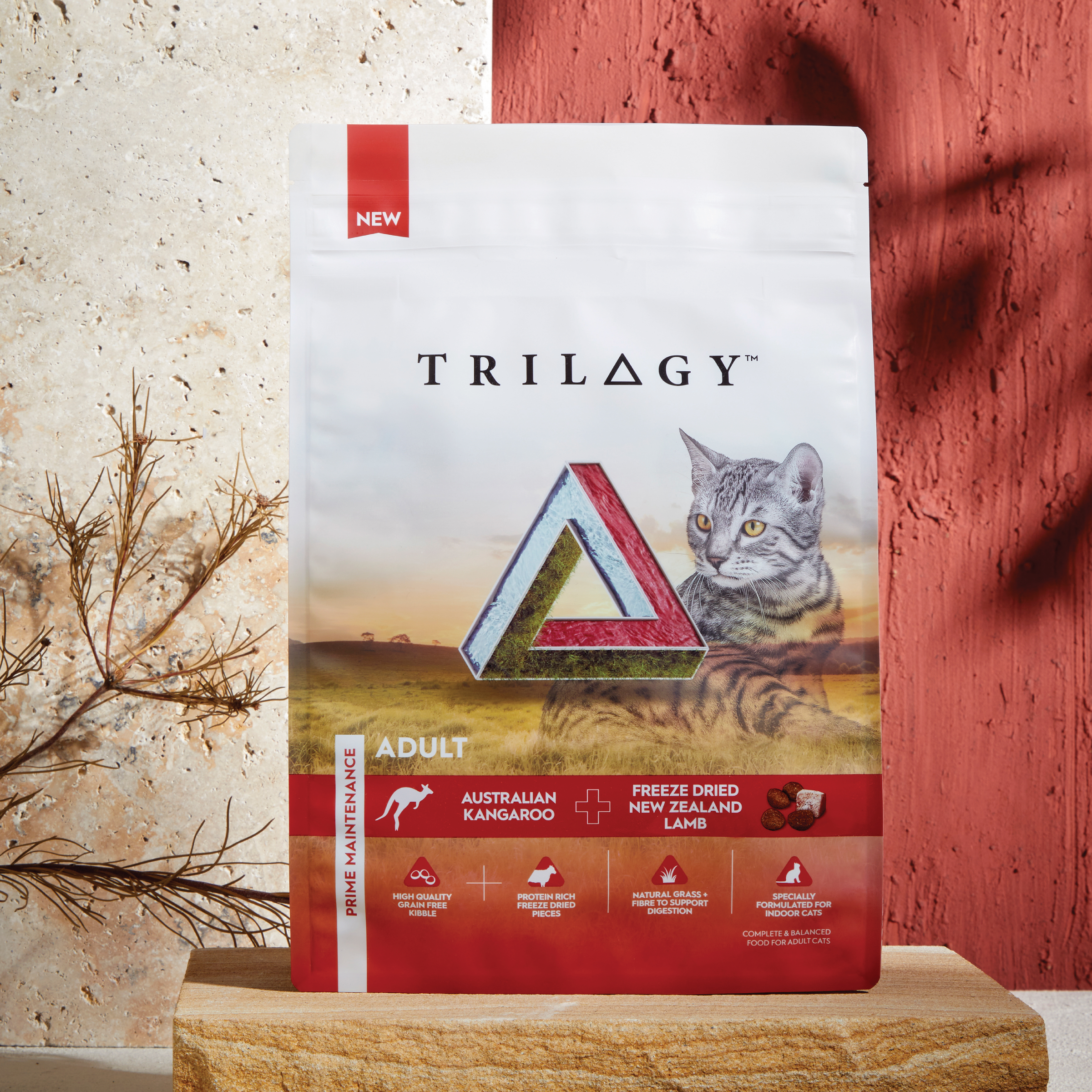 Trilogy Kangaroo dry cat food bag on a wooden stand against a red wall, lifestyle shot