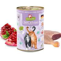 GranataPet DeliCatessen Duck & Poultry tin in purple livery, beside a raw duck leg and a halved pomegranate