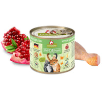 GranataPet DeliCatessen Kitten Junior Poultry tin, a short 200g can, beside a raw poultry leg and pomegranate