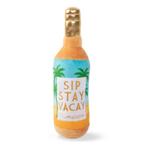Fringe Studio Sip Stay Vacay plush dog toy, orange and blue bottle with palm trees.
