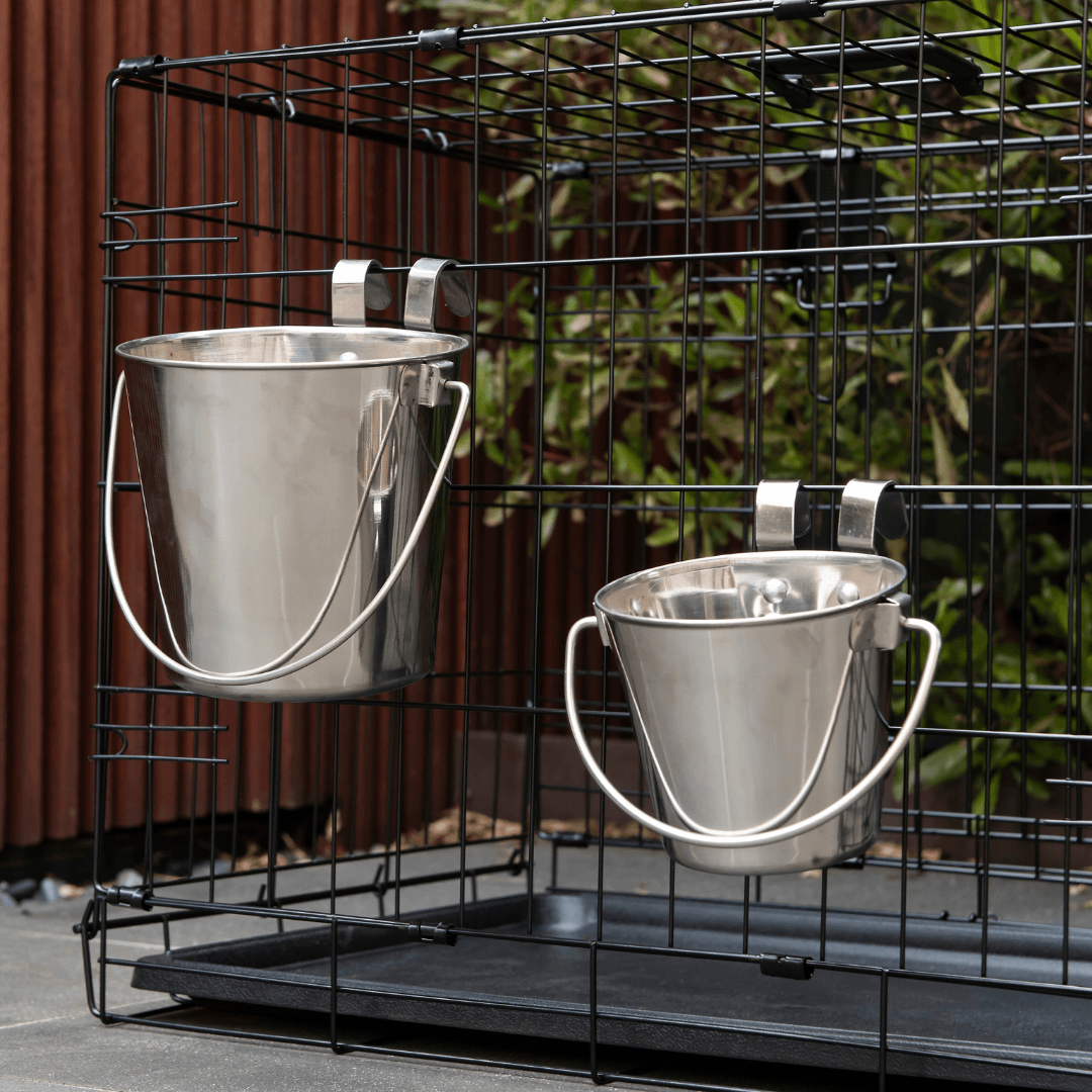 Two Superior Pet Goods flat sided stainless steel buckets hooked onto a wire crate
