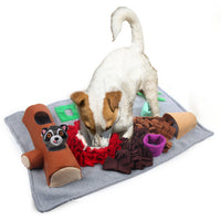 A white terrier digging in the All for Paws AFP Dig It treat mat with its log and raccoon toys