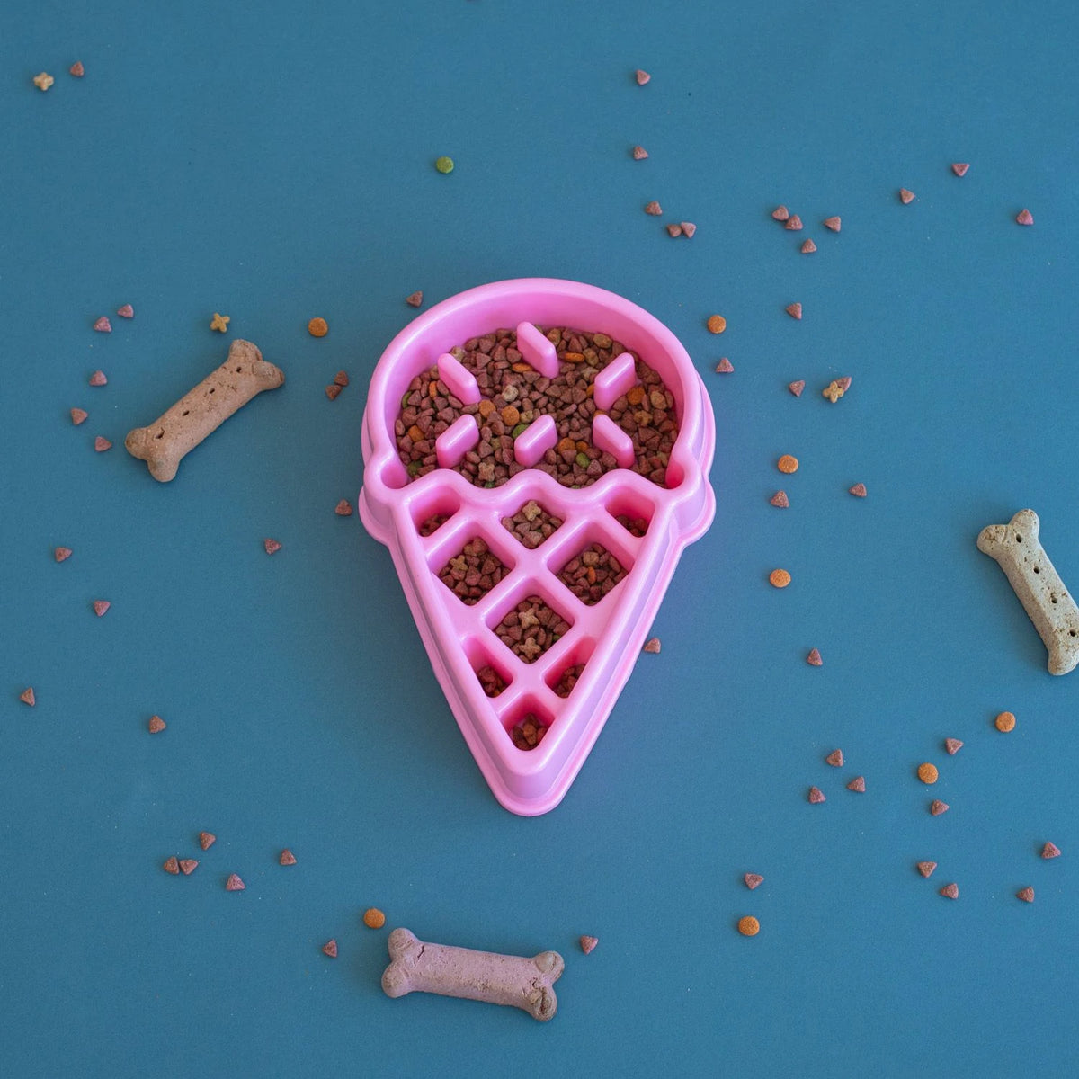 Zippy Paws ice cream shaped slow feeder bowl filled with kibble on a blue backdrop