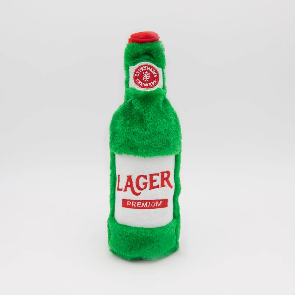 Zippy Paws Happy Hour Crusherz plush dog toy shaped as a lager beer bottle, on white