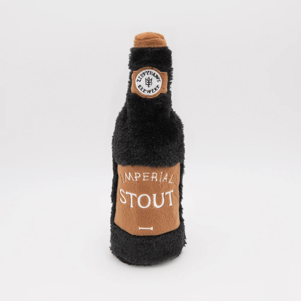 Zippy Paws Happy Hour Crusherz plush dog toy shaped as a stout beer bottle, on white